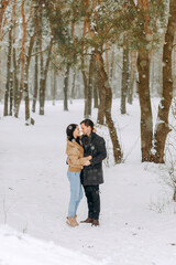 Fototapeta na wymiar Happy loving couple walking in snowy winter forest, spending christmas vacation together. Outdoor seasonal activities.