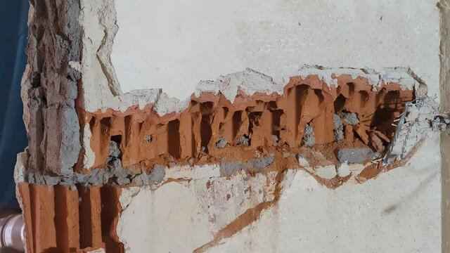 Hammer drill machine destructing a brick wall during renovation from the other side. The wall is crumbling when the drill hits the wall