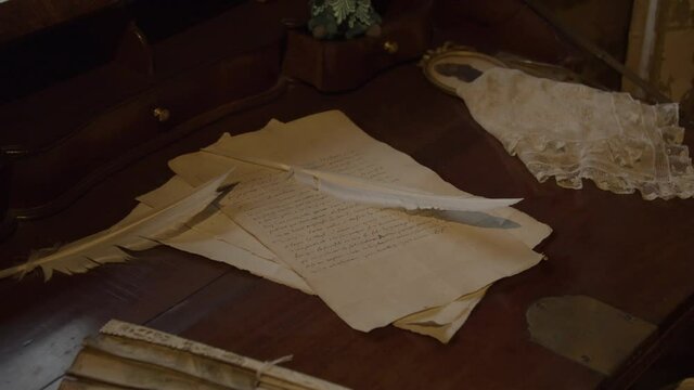 High angle pan over quills lying on old letter on a antique desk