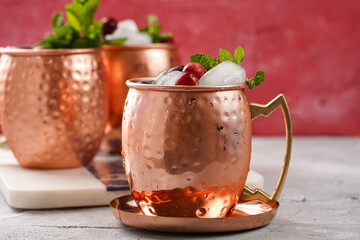 Traditional american alcoholic beverage moscow mule in copper mugs with cranberry and mint on white marble board - non-alcoholic cocktail version