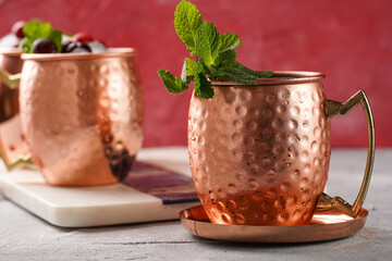 Traditional american alcoholic beverage moscow mule in copper mugs with cranberry and mint on white...