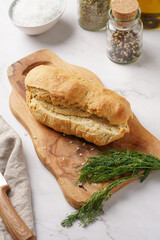 A loaf of homemade wheat bread on a wooden board on marble surface