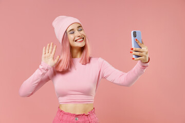 Fototapeta na wymiar Young woman 20s with bright dyed rose hair in rosy top shirt hat doing selfie shot on mobile cell phone waving hand isolated on plain light pastel pink background. People lifestyle fashion concept