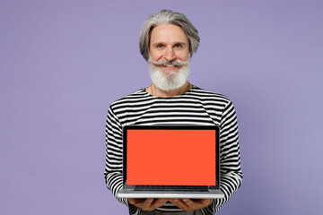 Elderly gray-haired mustache bearded man 60s in striped turtleneck hold use work on laptop pc...