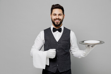 Young happy fun barista male waiter butler man 20s wear white shirt vest elegant uniform work at...