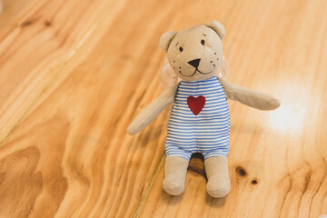 Cut little rabbit doll sitting on wooden table, decoration item in coffee shop, fabric toy