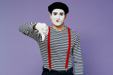 Frowning upset distempered unnerved young mime man with white face mask wears striped shirt beret showing thumb down dislike gesture isolated on plain pastel light violet background studio portrait.