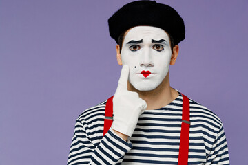 Fototapeta na wymiar Frowning distempered aggrieved displeased sullen young mime man with white face mask wears striped shirt beret showing imaginary tear isolated on plain pastel light violet background studio portrait.