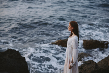 attractive woman in white dress posing by the ocean nature