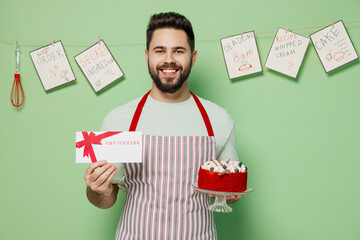 Young male chef confectioner baker man in striped apron hold cake gift certificate coupon voucher...