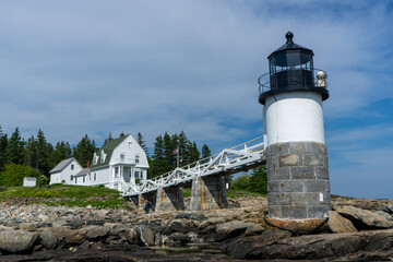 Beautiful white house and Marshall Point Lighthouse with the background of pine trees, Maine, USA