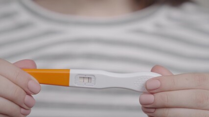 pregnancy test in a woman's hand, an alarming result of two strips, girl's period is delayed, healthy mother is expecting little baby, female joy and serious disorders, home medical check-up