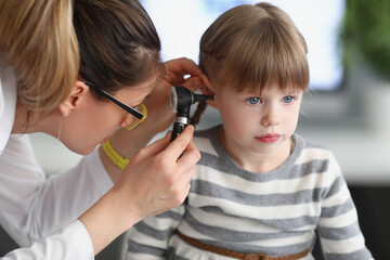 Little girl sit calm while family doctor examine ears with special equipment