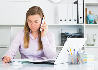 Obraz na płótnie Canvas Female employee having conversation on phone during work