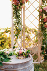 Wooden barrel decorated with roses stands next to a folding wedding screen