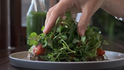 Slow-motion of a human hand dropping green leaves on the healthy dietary vegan fresh salad on organic lunch