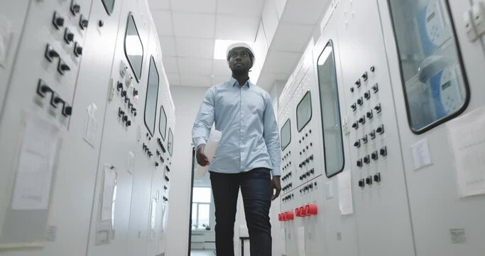 Portrait of an engineer in a hard hat at the production blueprint in hands.