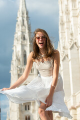 Street style photo of crazy fashionable woman wearing trendy clothes. Model walking in street of European city. Movement excited smiling woman.