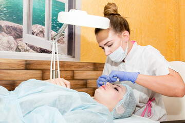 Lip augmentation. Beautician injects hyaluronic acid into the lips of a girl with a syringe. The...