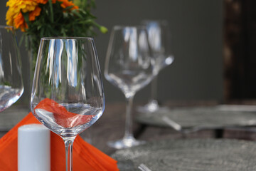 Wine glasses on rustic outdoor table setting with orange flowers and napkin