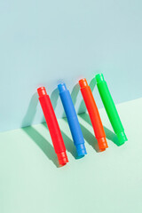 The straight folded pop tube stands leaning against the wall. Modern still life with antistress toy