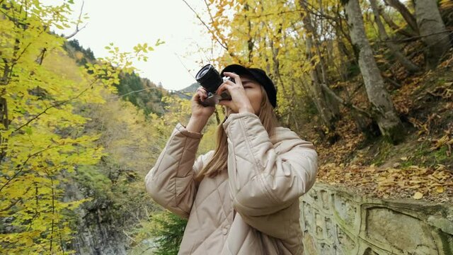 Beautiful traveler young woman takes picture on dslr camera. Blogger creates content. Beatiful Russian girl taking pictures in nature.  autumn forest.  4K.