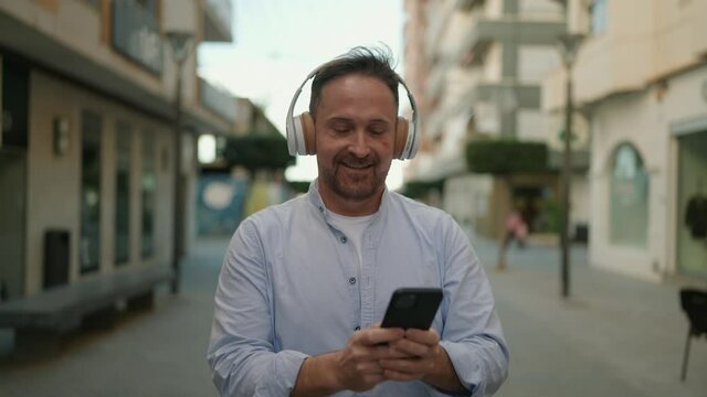 Young caucasian man smiling confident listening to music at street