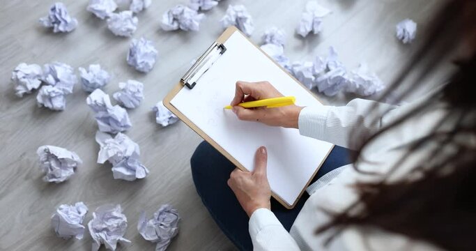 Woman sitting on floor near crumpled and scattered papers and writing business plan closeup 4k movie slow motion