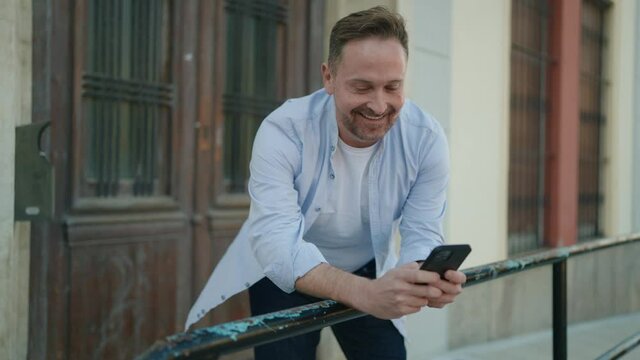 Young caucasian man smiling confident using smartphone at street