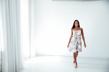 beautiful tanned woman in a summer dress in a white room