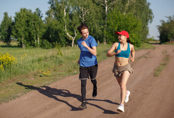 A young man and a woman run together outdoors