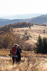 Old adult people with large backpacks hike through the autumn mountains, the concept of active recreation and active live in old age