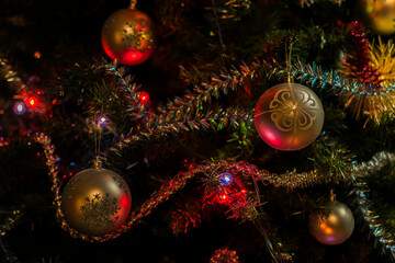 Beautiful Christmas tree decorations: balls, tinsel, a luminous garland on a dark green background. Festive mood.