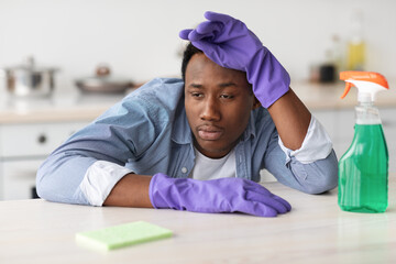 Tired black guy in gloves with spray bottle and sponge