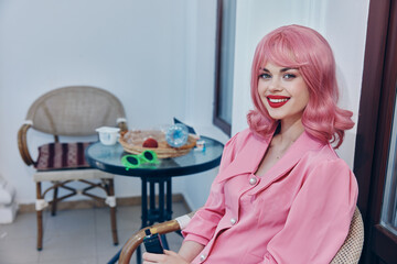 woman with pink hair sitting in a vintage cafe armchair relaxing