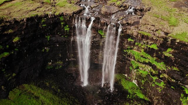 Aerial view of stunning waterfall in Faroe Islands. Aerial view of Fossa waterfall. Cloudy weather,establishing shot, no people. Majestic waterfall in wild rocky hillside. High quality footage.