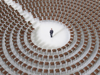 businessman standing in a circle of empty chairs