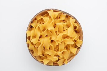 Raw pasta in bowl on old wooden table.