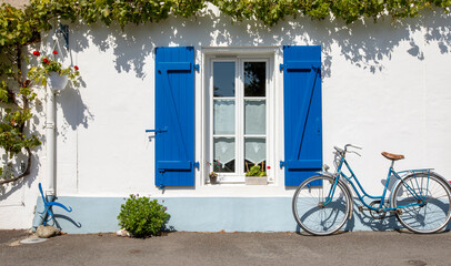 Vieux vélo bleu en façade d'une maison sur l'île de Noirmoutier en Vendée.