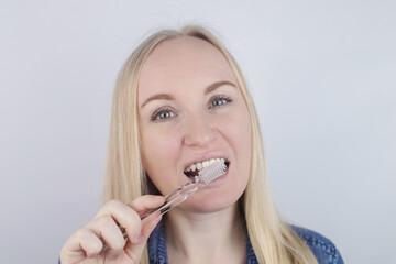 Close-up of a girl brushing teeth and look in front of a mirror. Oral hygiene. In the hands of objects for cleaning the oral cavity: a toothbrush and paste. Isolated on white background.