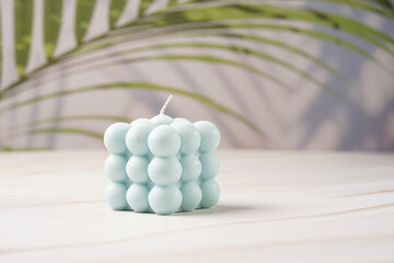 One blue square bubble candle on a tropical background