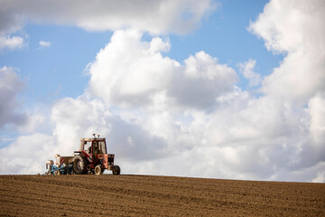 Fototapeta premium Paysan au volant de son tracteur labourant les champs au printemps.