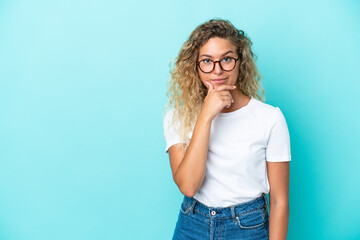 Girl with curly hair isolated on blue background thinking