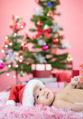 Happy cute baby wearing Santa hat with Christmas pink background