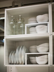 White kitchen porcelain dishes and plates stand on a white shelf