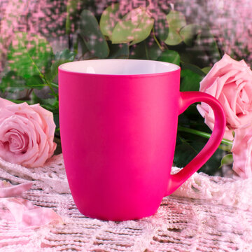 Pink tea mug on lace napkin with rose decoration.