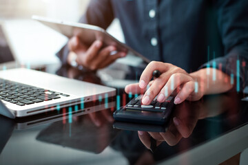 Investors are calculating on calculator investment costs and holding tablet in hand.