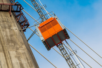 Fototapeta na wymiar Construction elevator, lifts workers towards the new cable-stayed bridge under construction. Construction equipment.