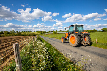 Tracteur roulant à vive allure sur une route de campagne au milieu des champs.