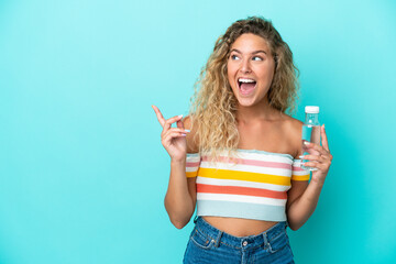 Young blonde woman with a bottle of water isolated on blue background intending to realizes the solution while lifting a finger up
